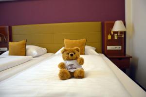 a teddy bear sitting on top of a bed at Austria Classic Hotel Wien in Vienna