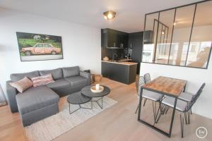 een woonkamer met een bank en een tafel met stoelen bij Lily a la mer du Zoute in Knokke-Heist
