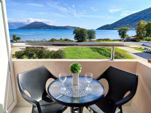 einen Tisch und Stühle auf einem Balkon mit Blick auf das Wasser in der Unterkunft Apartments Monako in Herceg-Novi