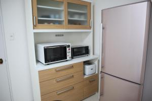 a kitchen with a microwave and a refrigerator at STAY Moiwayama201 in Sapporo
