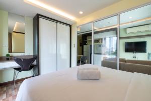 Greenview Ekkamai10 Suite في بانكوك: غرفة نوم بسرير ابيض وغرفة معيشة