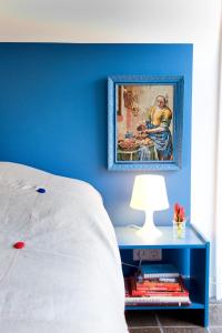 a blue bedroom with a bed and a table with a lamp at Jackie O Studio in Amsterdam