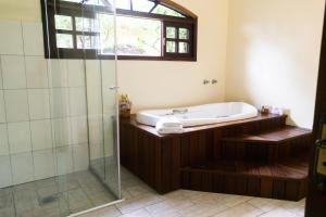 a bathroom with a tub and a glass shower at Hotel Naturalis in Paranaguá +134 photos