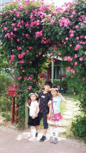 dos niños parados bajo un arbusto de rosas rosas en Bellus-Rose Pension Gyeongju en Gyeongju