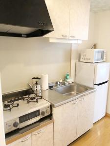 a kitchen with a stove and a sink and a microwave at ピオーレ大手門501 in Susakiuramachi
