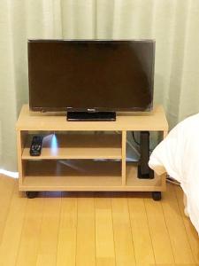 a television on a wooden stand with a remote control at ピオーレ大手門501 in Susakiuramachi