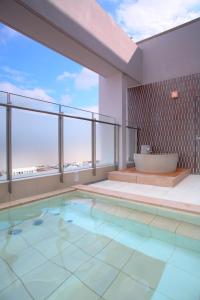 a bathroom with a swimming pool and a bath tub at Spa Hotel Alpina Hida Takayama in Takayama
