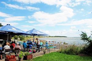 a group of people sitting at tables by the water at Haus Friedenswinkel in Thiessow