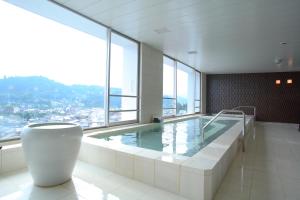 ein großer Pool in einem Gebäude mit einem großen Fenster in der Unterkunft Spa Hotel Alpina Hida Takayama in Takayama