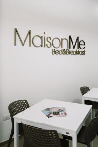 uma mesa branca com cadeiras e uma placa na parede em MaisonMe em Vasto