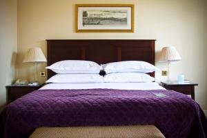 een groot bed met een paarse deken en witte kussens bij Ansty Hall in Coventry