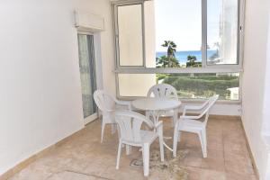 einen weißen Tisch und Stühle in einem Zimmer mit Fenstern in der Unterkunft B&B Cote D'azur in Hammamet