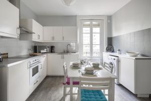 een keuken met witte kasten en een tafel en stoelen bij Côté Rivière in Rennes