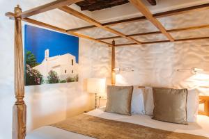 a bedroom with a bed with a painting on the wall at Agroturismo Atzaró in Santa Eularia des Riu