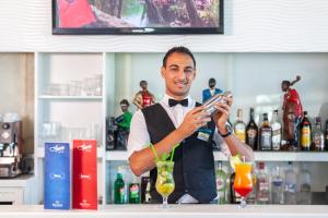 a man standing behind a bar holding a drink at Hotel Nour Congress & Resort in Bizerte