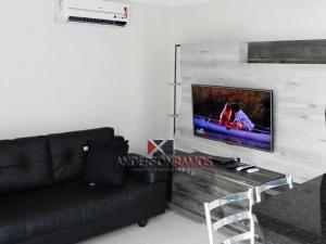 sala de estar con sofá negro y TV de pantalla plana en 1022 - Apartamento com vista para o mar de Bombinhas - Residencial Areia Branca Apto 301, en Bombinhas