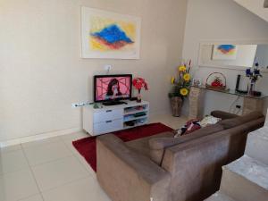 uma sala de estar com um sofá e uma televisão em Casa 1/4 Chapada Diamantina/ibicoara em Ibicoara