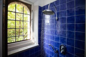 a blue tiled bathroom with a shower and a window at Quel Castello di Diegaro in Cesena