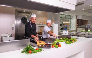 two chefs standing in a kitchen preparing food at Hotel Nour Congress & Resort in Bizerte