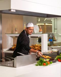 a chef preparing food in a restaurant kitchen at Hotel Nour Congress & Resort in Bizerte