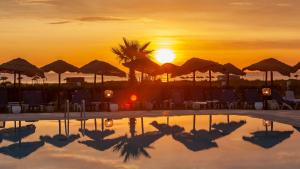 a pool with the sun setting in the background at Hotel Nour Congress & Resort in Bizerte