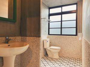 uma casa de banho com um lavatório, um WC e uma janela. em 眷待期休憩所眷村民宿 em Kaohsiung