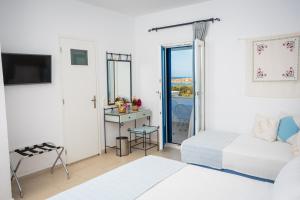 a white room with two beds and a television at Pyrgaki Hotel in Parikia