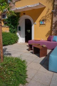 un divano viola e un tavolo sul patio di Locanda Sant'Andrea Hotel & Relais a San Pantaleo