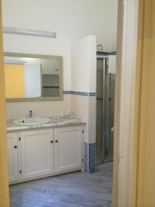 y baño con lavabo y ducha con espejo. en Casa Ilva en La Maddalena