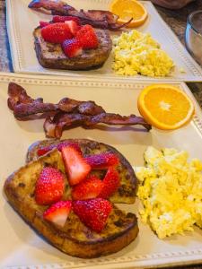 two plates of breakfast foods with strawberries and bacon at Woodbridge Inn Bed & Breakfast in Woodstock