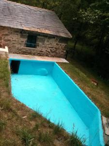 una piscina blu accanto a una casa in pietra di Molino de Louzao a Palas de Rei