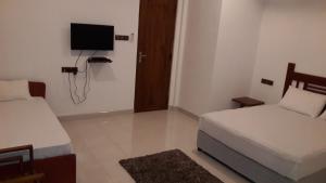 a small room with two beds and a television at Risenlak Holiday Resort in Polonnaruwa