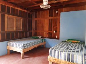 two beds in a room with wooden walls at Cabañas jaysur in Barra de la Cruz