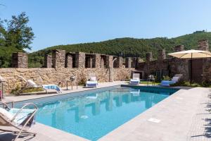 a swimming pool with chairs and an umbrella at Antica Pergola di San Giusto in Capannori