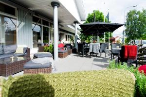 a patio with chairs and tables and an umbrella at Wärdshuset Bredaryd in Bredaryd