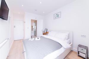 a white bedroom with a bed and a flat screen tv at Quiet cosy rooms in Harrow