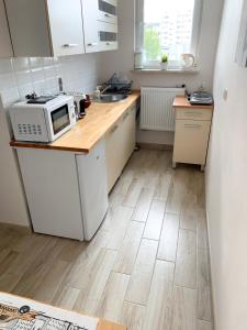a kitchen with white cabinets and a wooden floor at Apartament Kotwica in Gdynia