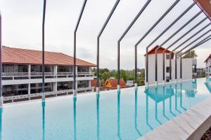 a large swimming pool in a building with large windows at Palmyrah Surin Apartments by Beringela in Surin Beach