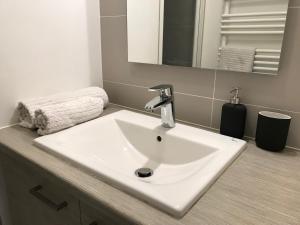 La salle de bains est pourvue d'un lavabo blanc et d'un miroir. dans l'établissement Chambre d'hôte Naos Homestay, à Boulogne-Billancourt