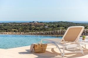 une chaise blanche assise à côté de la piscine dans l'établissement Agroturismo Llucasaldent Gran Menorca - Adults Only, à Son Bou