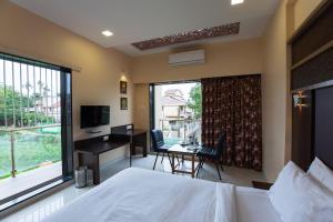 a bedroom with a bed and a desk and a television at City Palace Resort in Lonavala