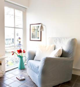ein Wohnzimmer mit einem Sofa und einer Vase mit roten Blumen in der Unterkunft Jackie O Studio in Amsterdam