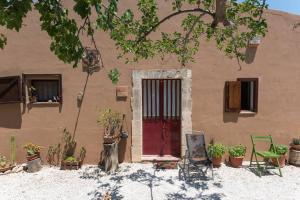 una casa con una puerta roja y un perro parado frente a ella en Agriturismo Terra Di Pace, en Noto