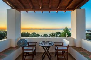 eine Terrasse mit einem Tisch und Stühlen sowie Meerblick in der Unterkunft Theonis Villas in Moutsoúna