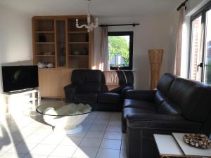 ミッデルケルケにあるLily's placeのリビングルーム(黒い革張りのソファ、テレビ付)