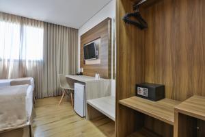 a hotel room with a bed and a sink and a desk at Nobile Inn Meridional Cariacica in Cariacica