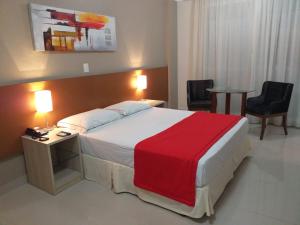 um quarto de hotel com uma cama grande e um cobertor vermelho em Alfa Hotel em Viçosa