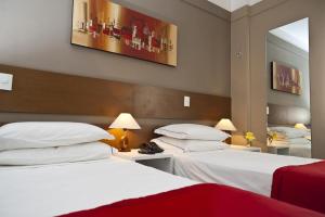 um quarto de hotel com duas camas e um espelho em Alfa Hotel em Viçosa