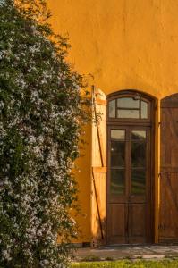 an orange building with a door and a flowering bush at Estancia Rincón del San Francisco in Paysandú