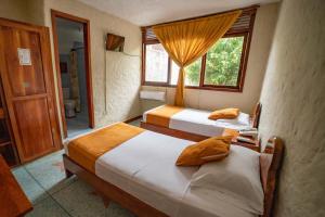 a bedroom with two beds and a window at Hostal Estrella de Mar in Puerto Ayora